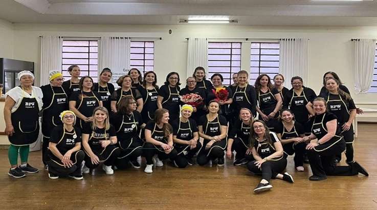 a group of women wearing black aprons posing for a photo